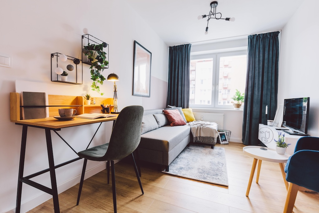 Furnished corporate housing living space with desk, sofa and natural light
